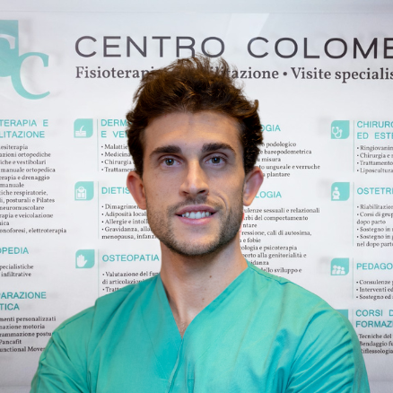 Ritratto professionale del Dott. Alessandro Grondona, ortopedico specializzato nella chirurgia della mano e del polso, in camice verde con braccia conserte, presso il Centro Colombo Genova.