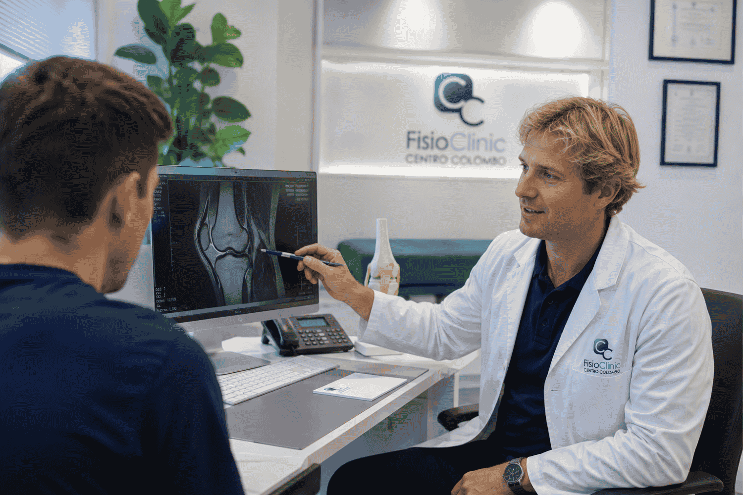 Fisiatra della FisioClinic mostra a un paziente la risonanza magnetica del ginocchio per valutare la gola intercondiloidea e una possibile sindrome del ciclope